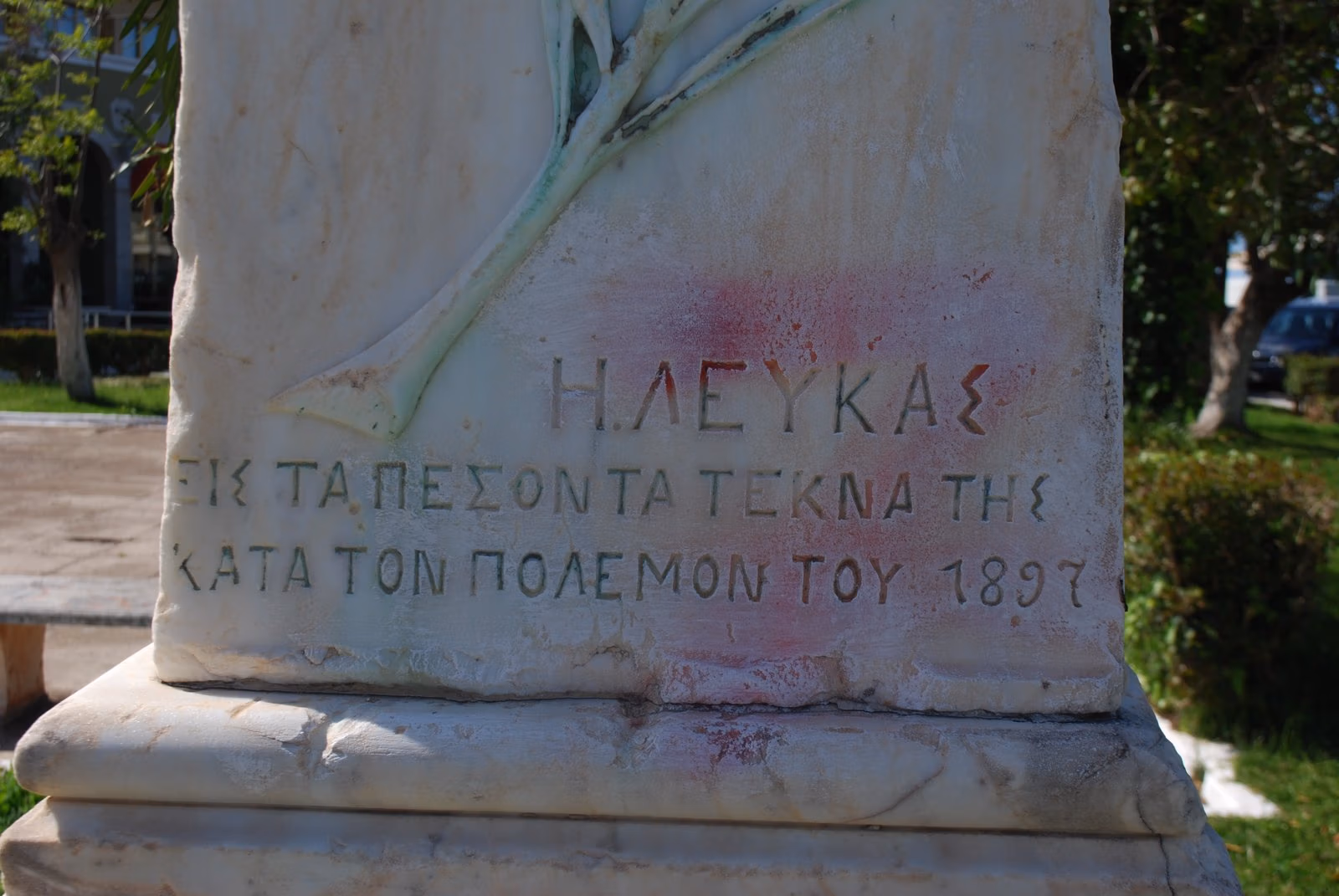 Close view of the carved Greek inscription to Lefkada's dead of the 1897 war, beneath a laurel relief, on the memorial shaft