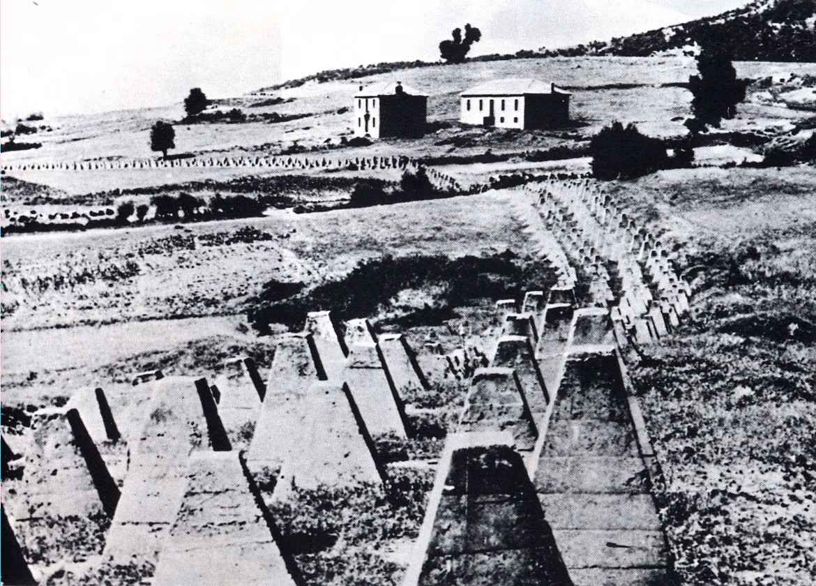 Rows of pyramidal concrete anti-tank blocks crossing a bare hillside